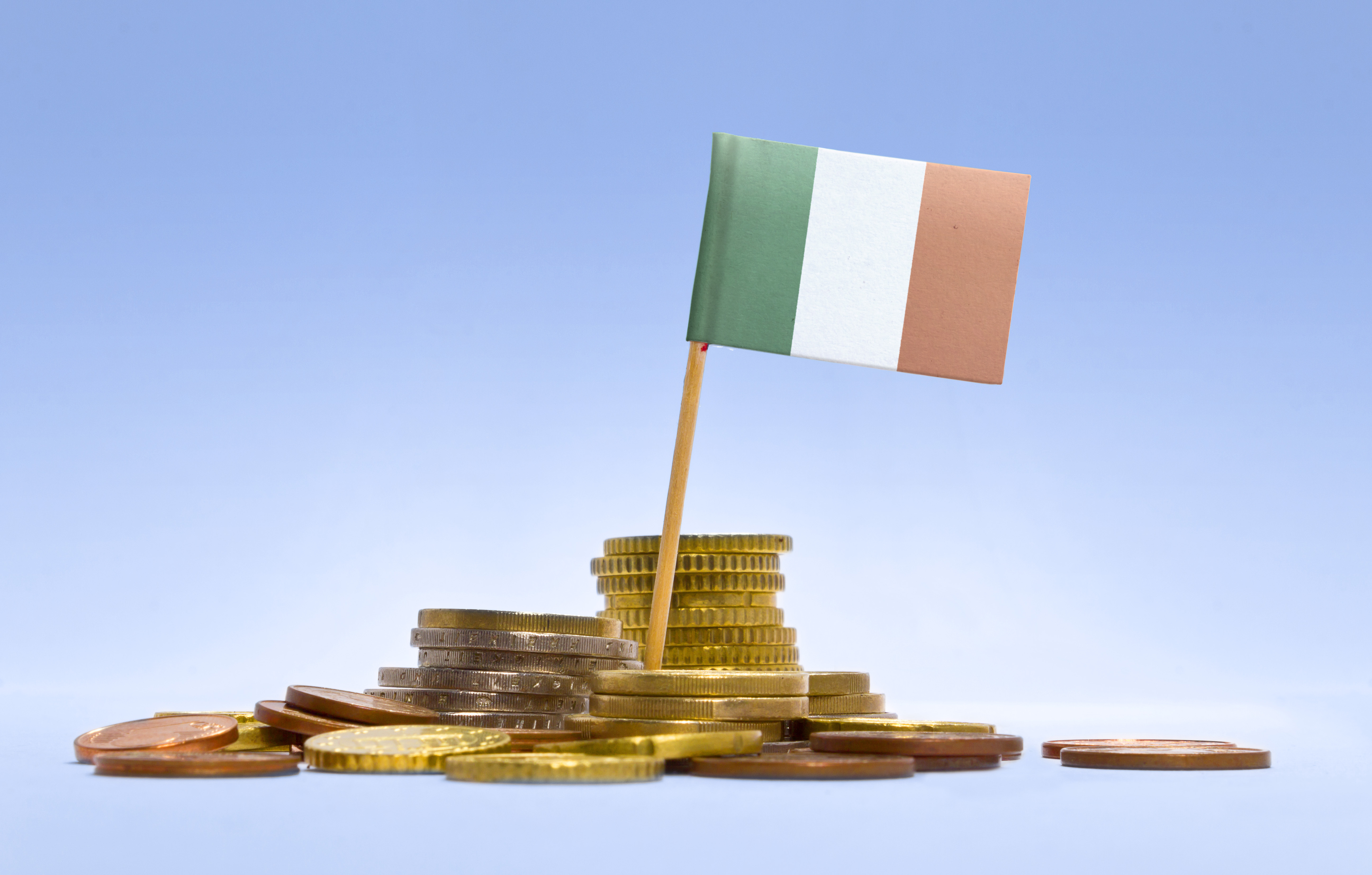 Flag of Ireland in a mixed stack of european coins and a blue background.(series)